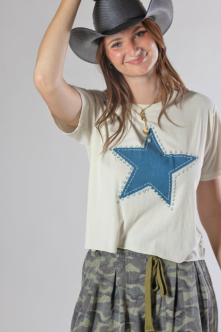 A woman wearing a Roger-Cowboy-Straw-Hat-Black, a cream-colored short-sleeve crop star top, and camouflage pants-FleaStyle