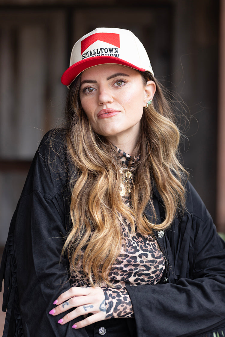 Woman wearing a red and white cap with 'Smalltown Smokehouse' embroidered patch and a black fringe jacket-FleaStyle 